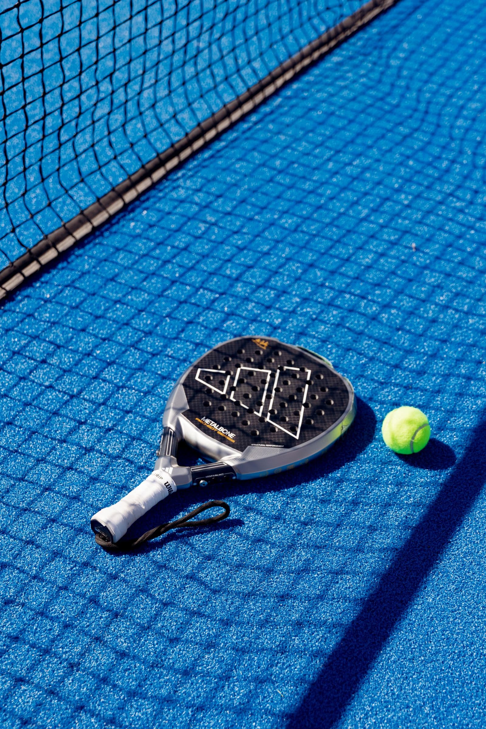 Padel racket and ball on a bright blue court